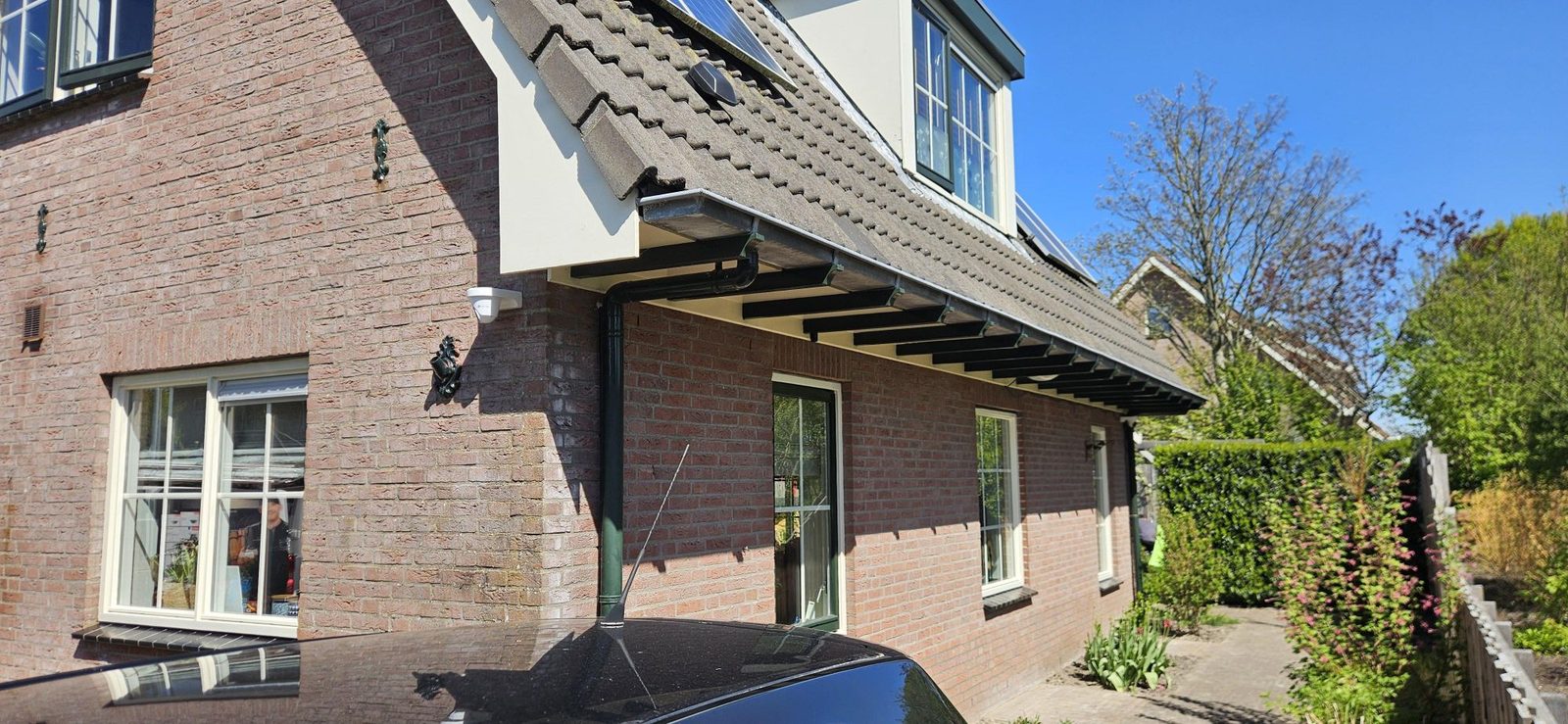 Woning met een camera onder de dakrand, zicht op oprit en voordeur