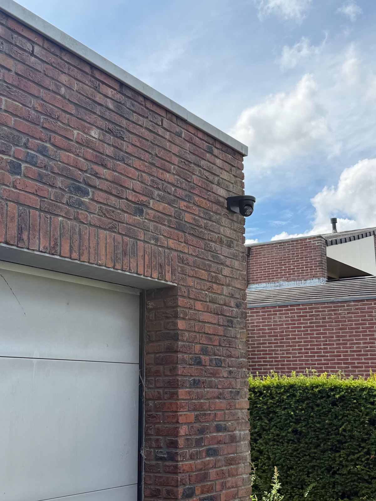 Zwarte camera op de hoek van een woning boven de garagedeur