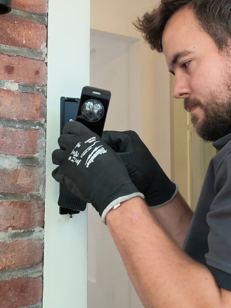 Monteur zet een videodeurbel vast naast de deur