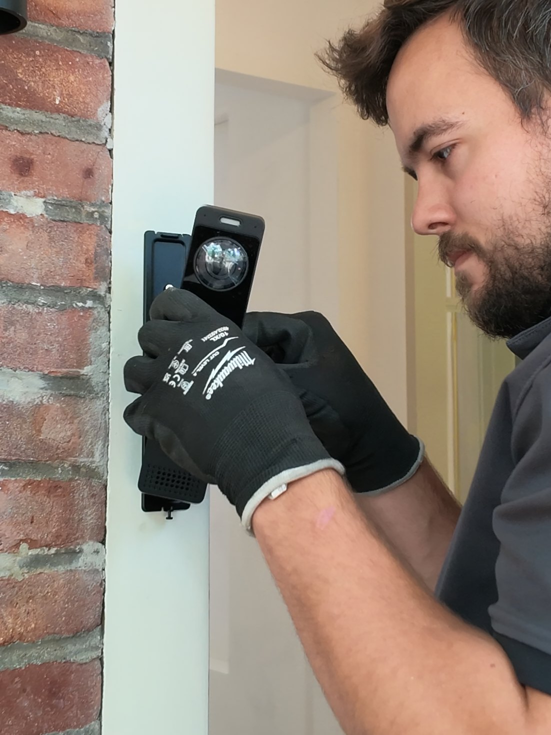 Monteur monteert een videodeurbel met camera naast de voordeur