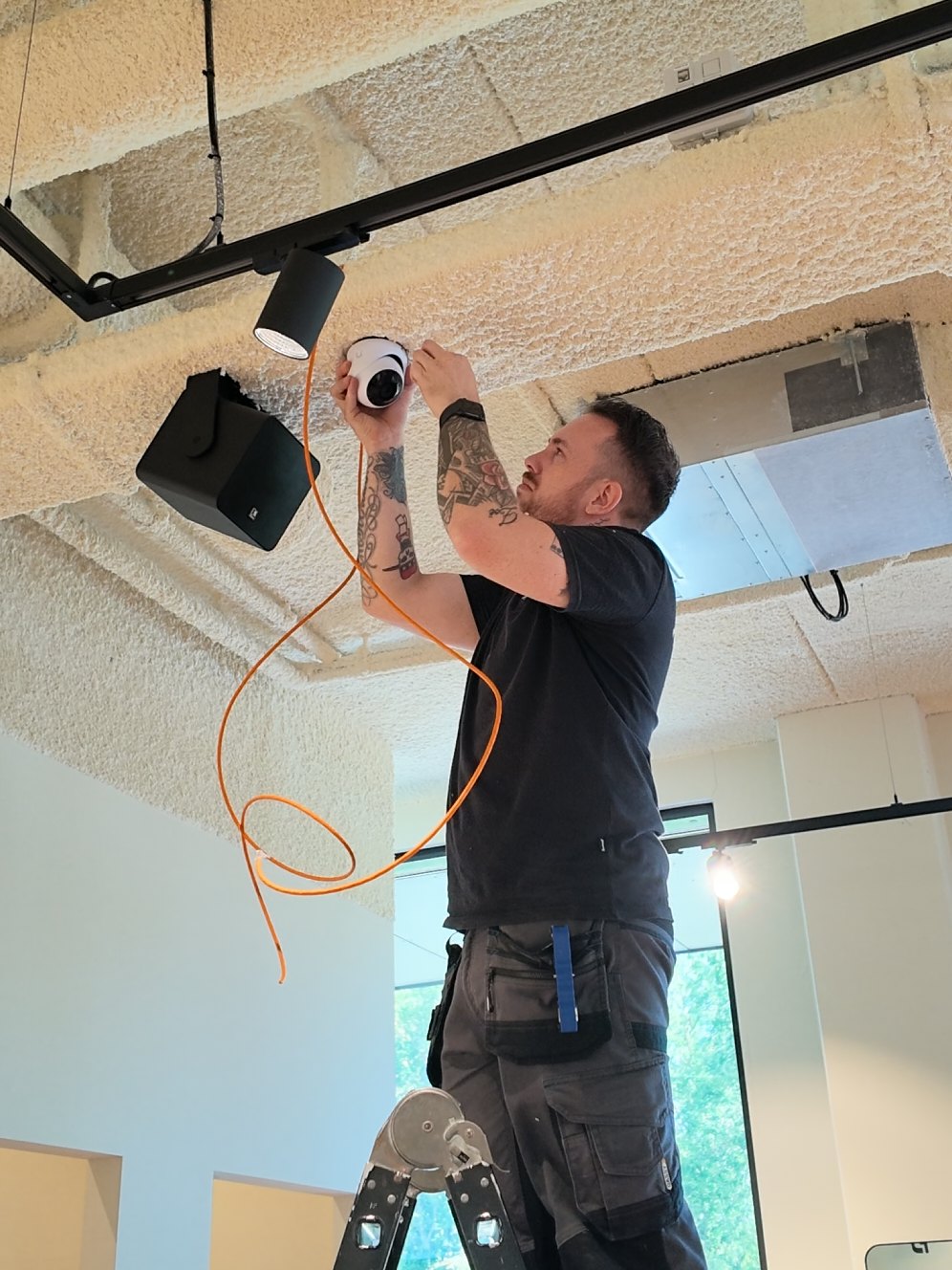 Monteur op een ladder monteert een koepelcamera aan het plafond