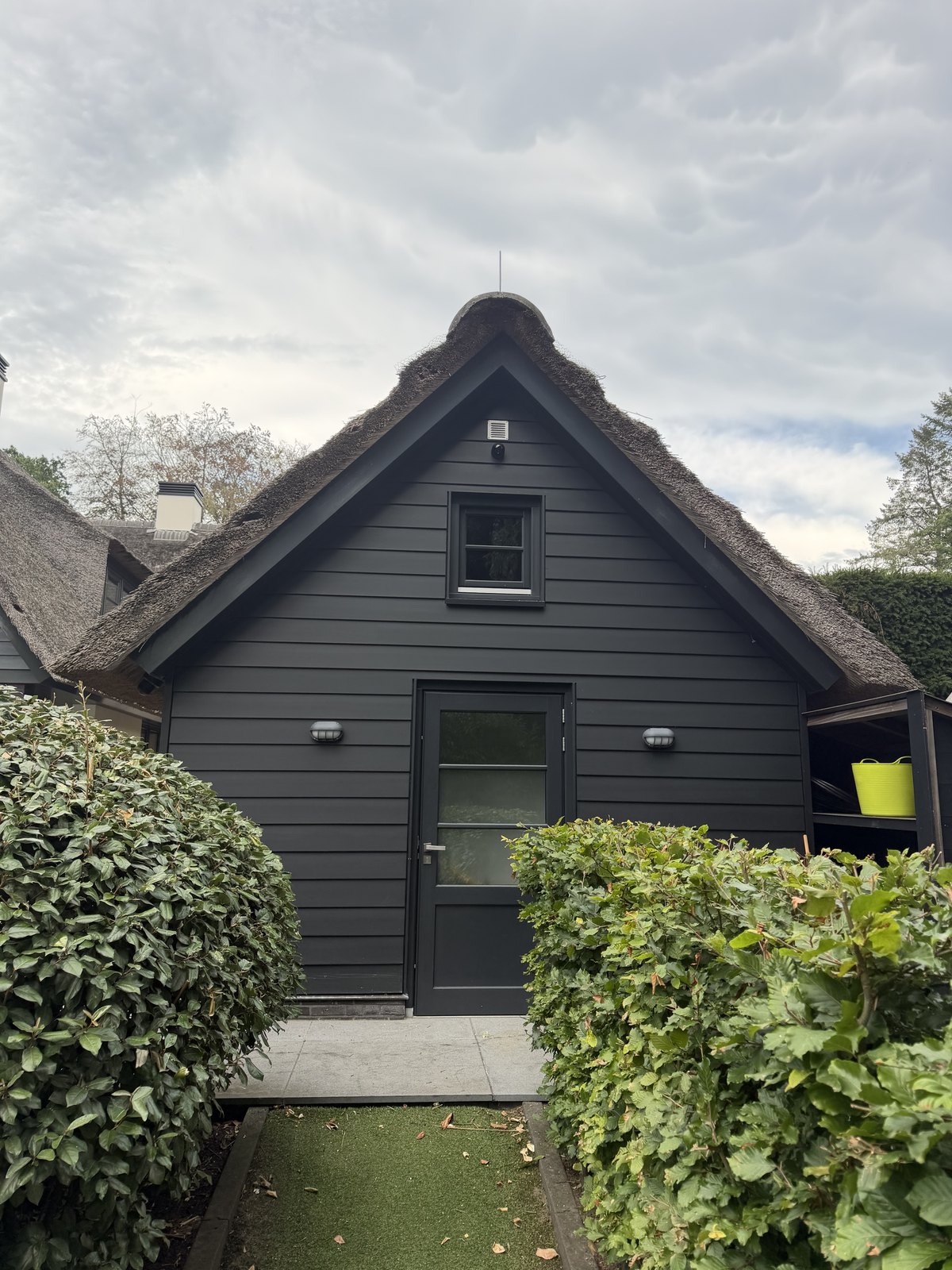Bijgebouw met rieten kap en een camera in de nok