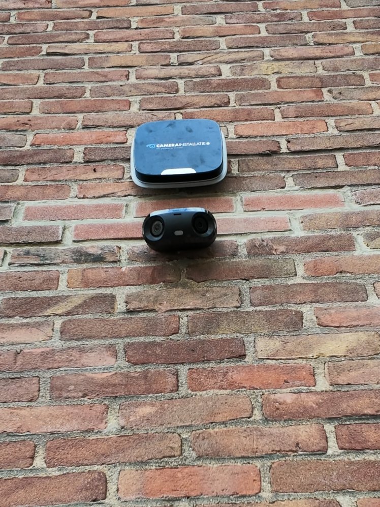 Buitensirene en camera samen op een bakstenen gevel