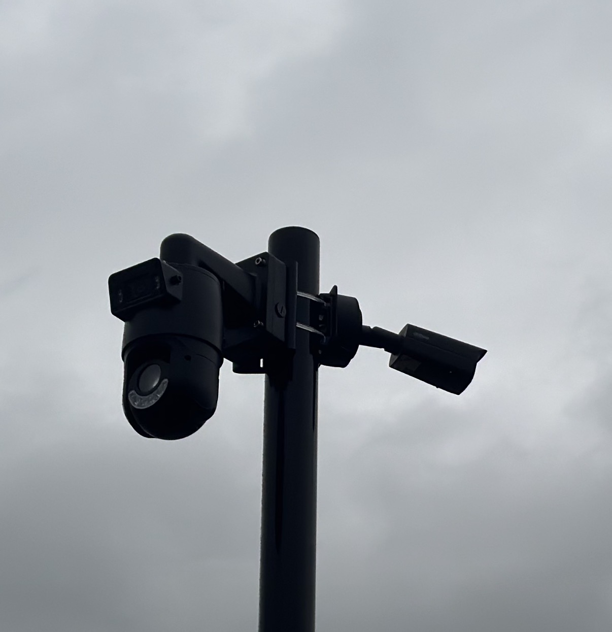 Een camera en een schijnwerper naast elkaar op dezelfde paal