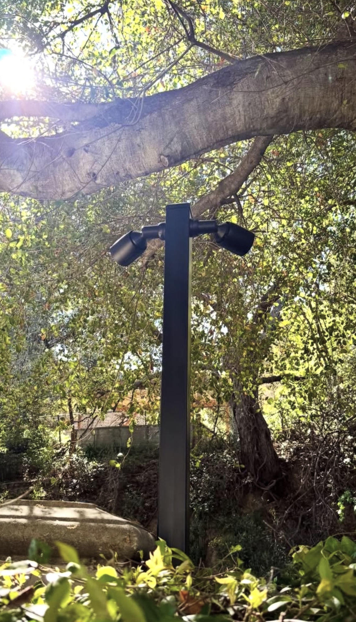 Twee buitenspots op een paaltje onder een boom