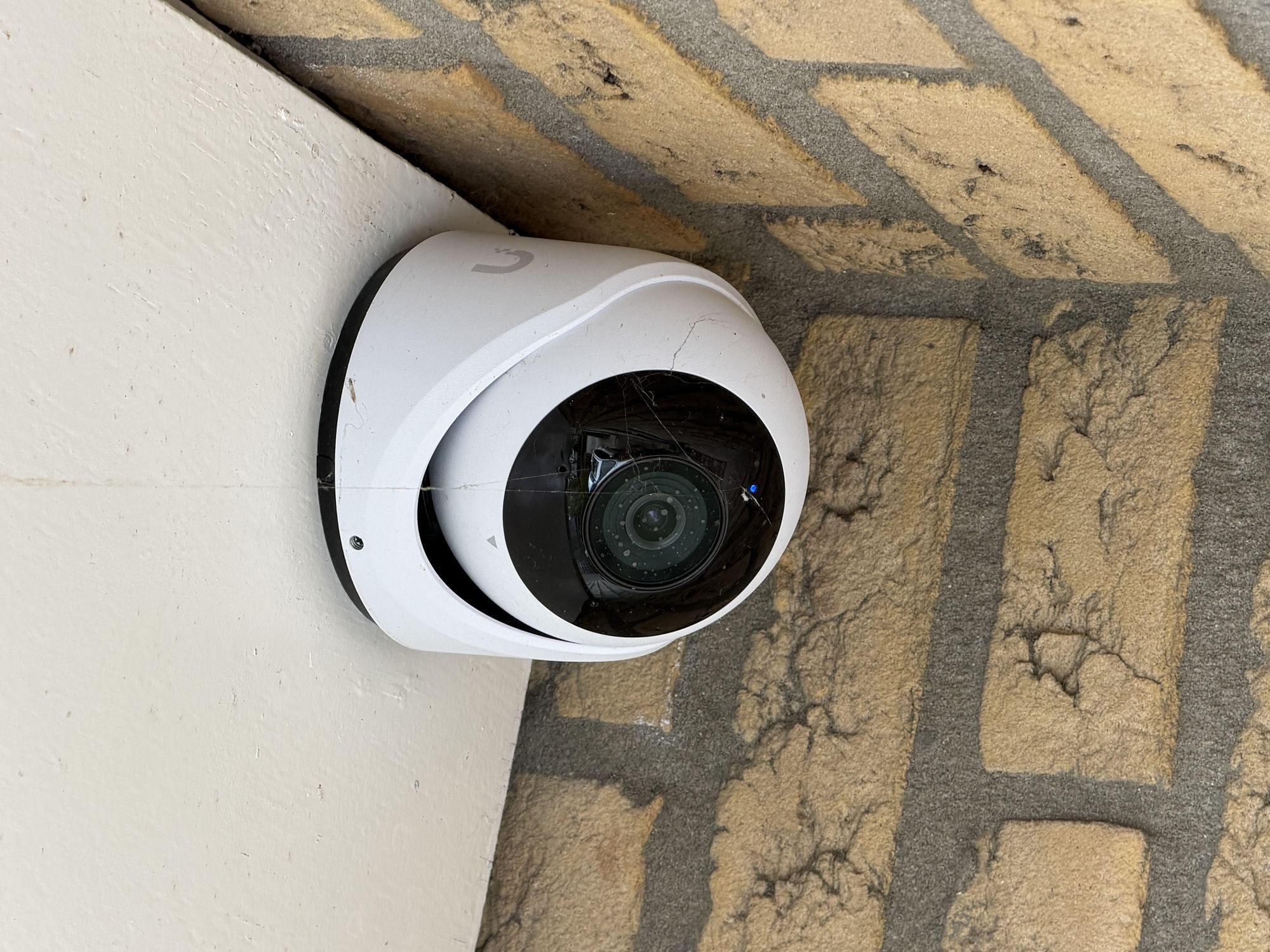 Witte koepelcamera met microfoon en luidspreker op de hoek van een gevel