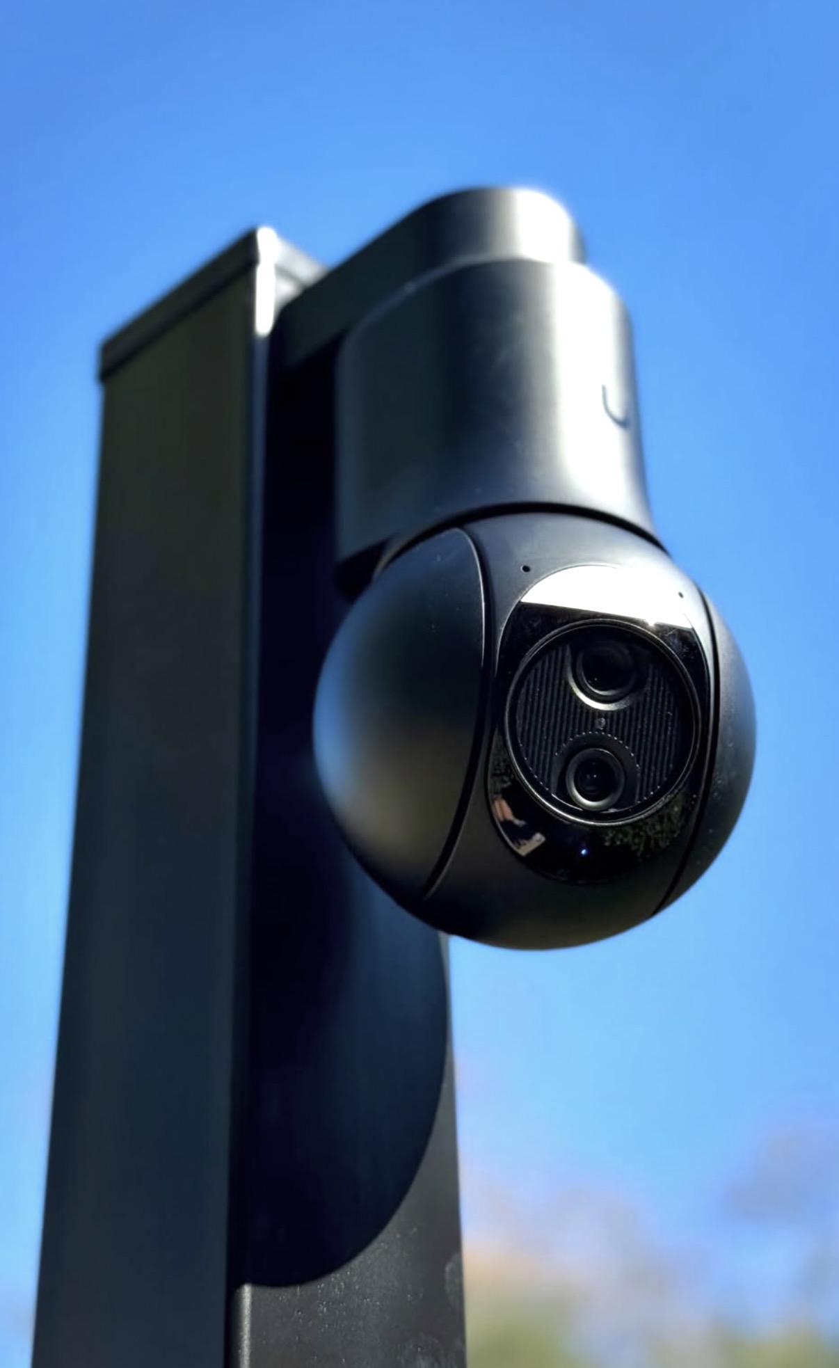 Zwarte draaibare camera op een slanke paal tegen een strakblauwe lucht