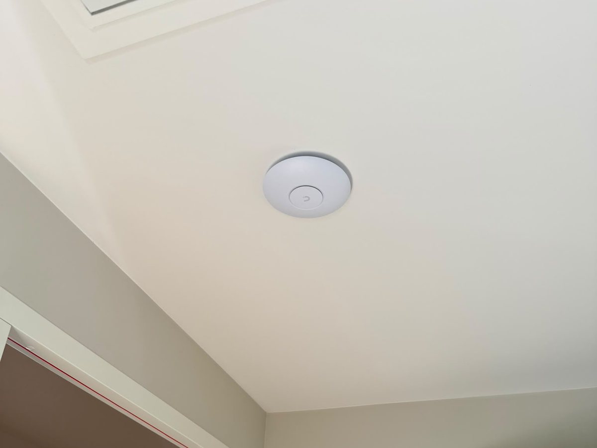 Wit access point aan het plafond van een overloop, naast het zolderluik