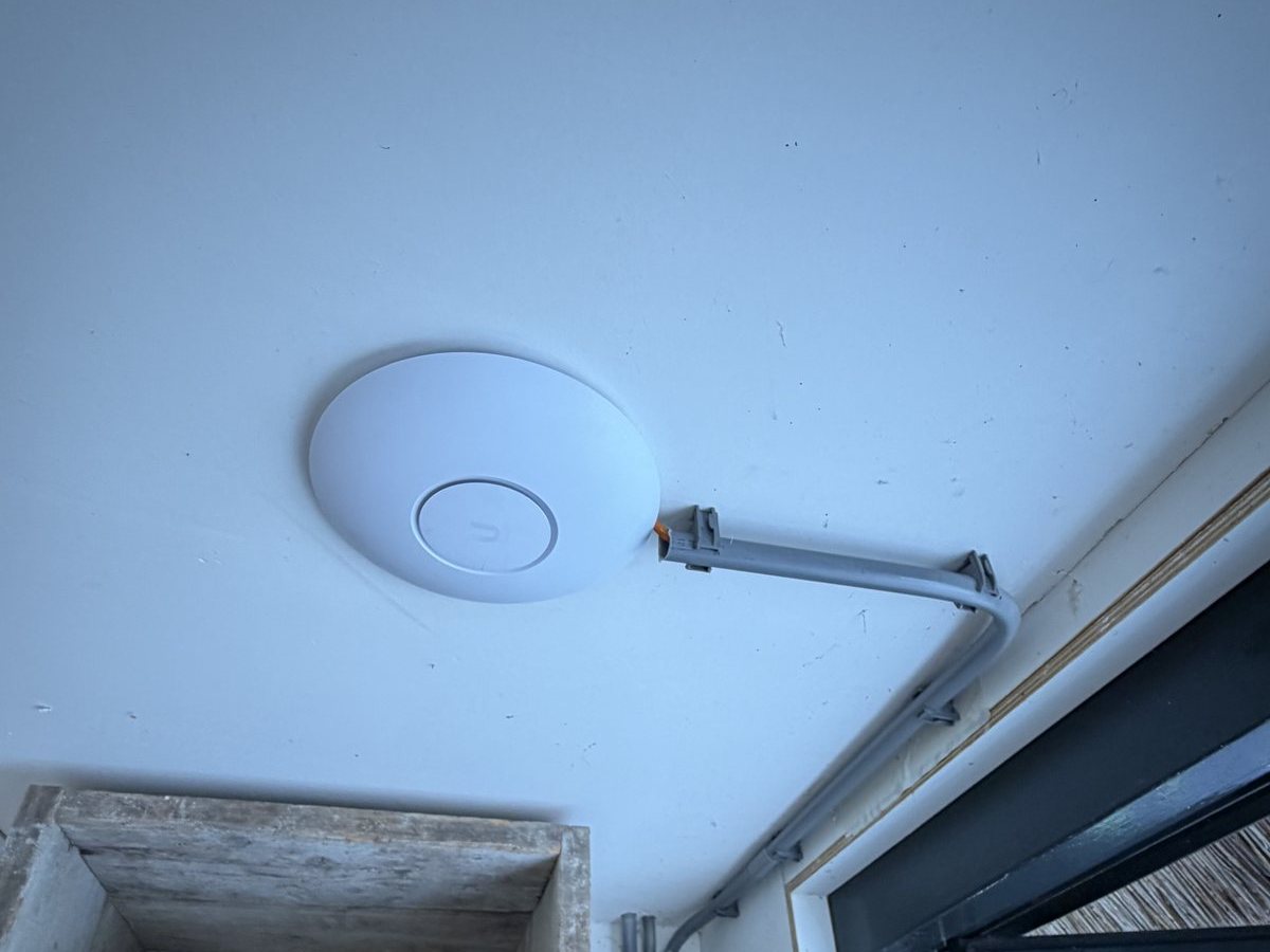 Wit access point aan de binnenmuur, met de kabel in een opbouwleiding