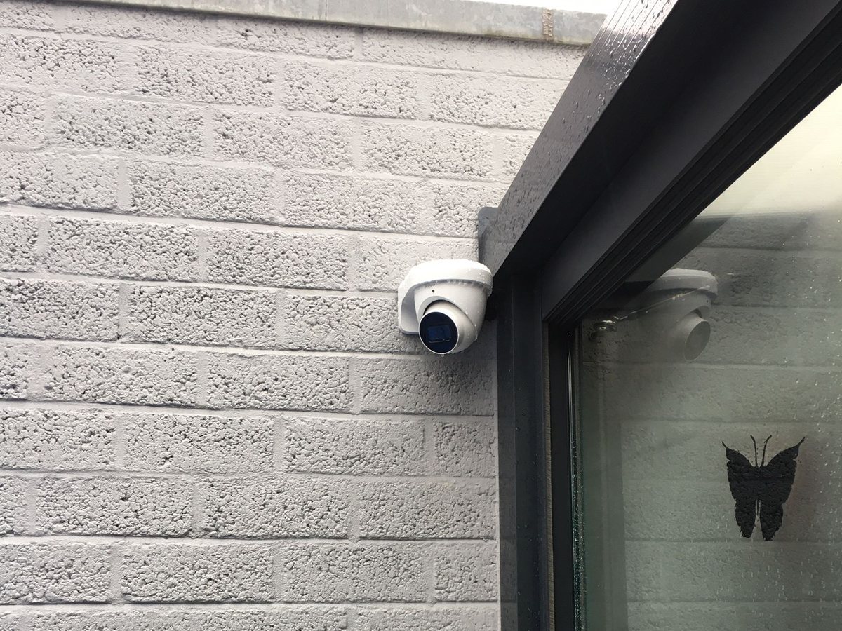 Witte domecamera onder de dakrand van een vakantiewoning met witte steen