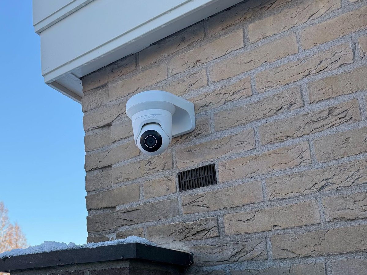 Witte camera hoog op de bakstenen zijgevel van een woning