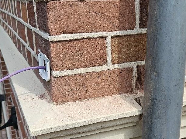 Netwerkkabel die via een kleine doorvoer in het voegwerk naar buiten komt