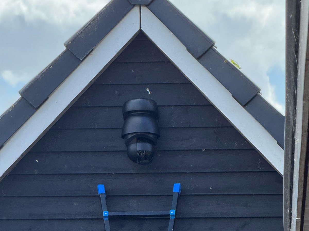 Zwarte draai- en zoomcamera hoog in de nok van een zwarte houten schuur