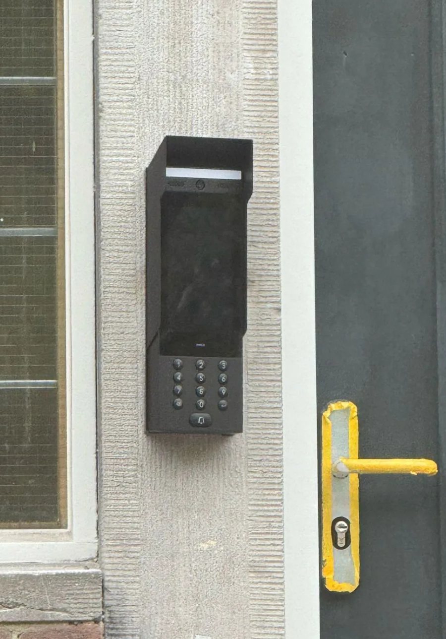 Zwarte intercom met toetsenbord op een natuurstenen deurpost naast de voordeur