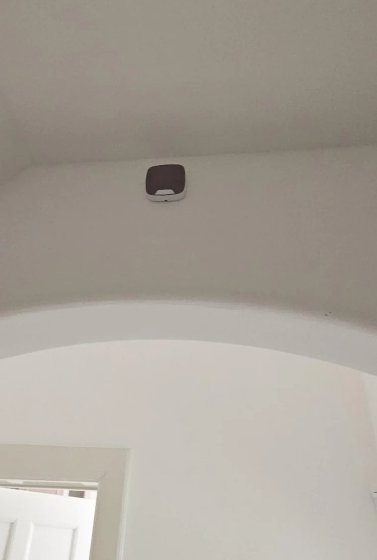 Lichte hal met een boog, hoog in de hoek een klein onderdeel van het alarm