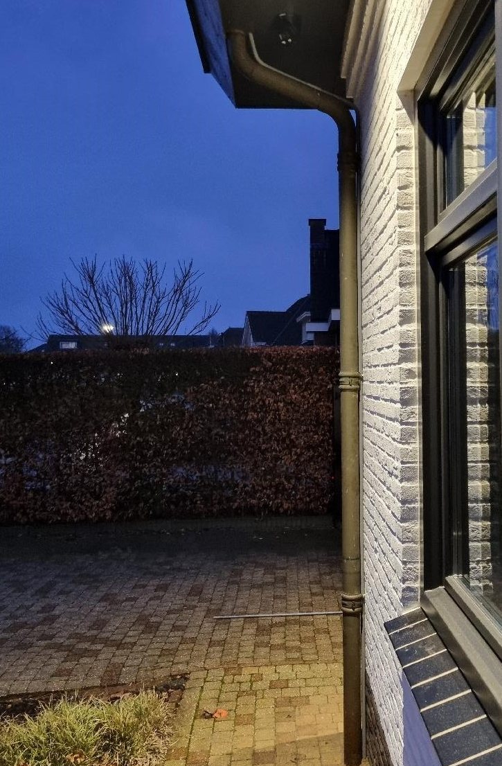 Zijgevel van de woning in de schemer, met de camera onder de dakrand