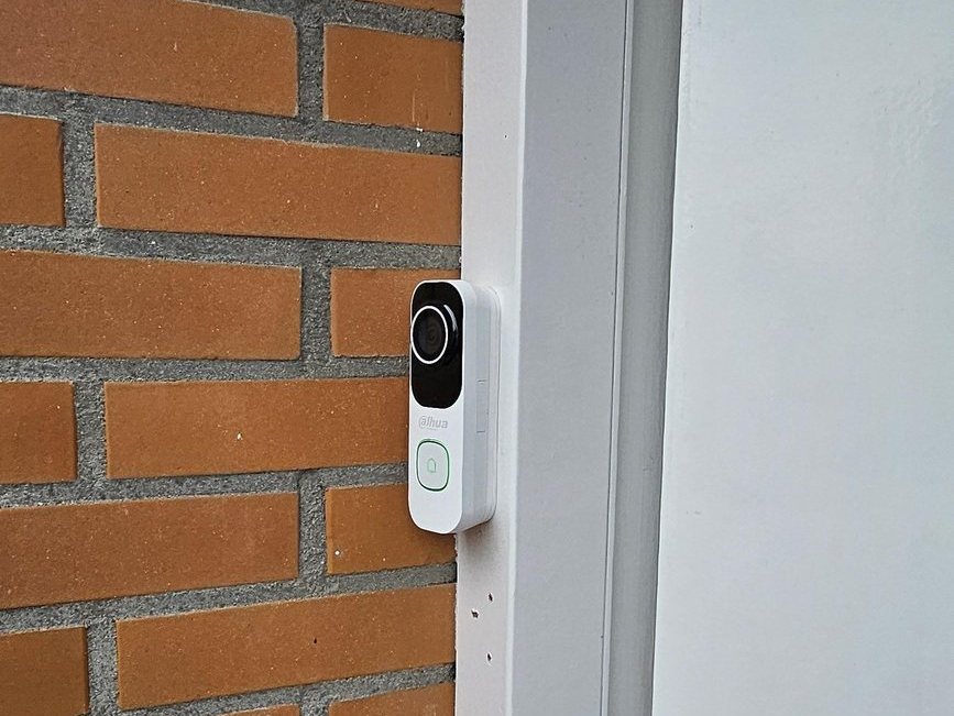 Witte videodeurbel op de gevel naast de voordeur