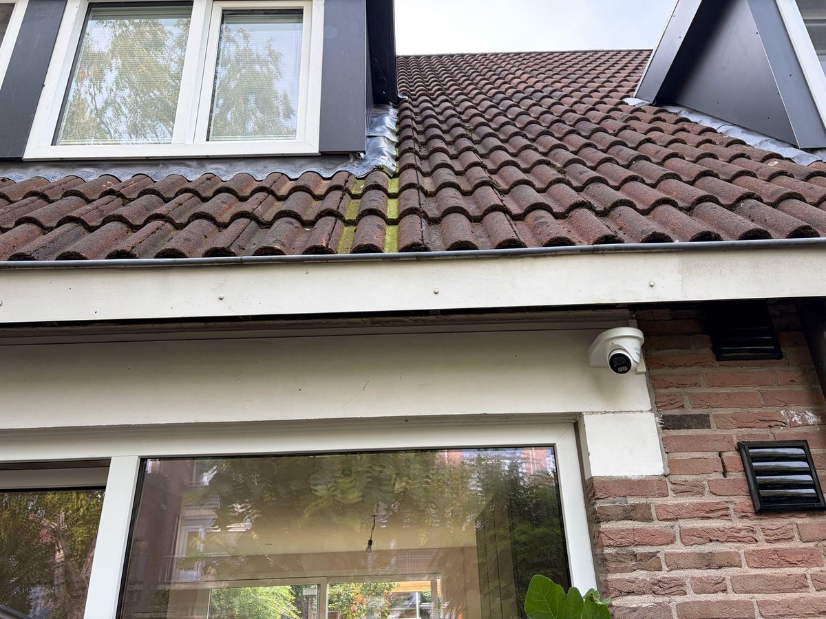 Witte VIGI-camera onder de dakrand, boven de tuindeur van een woning